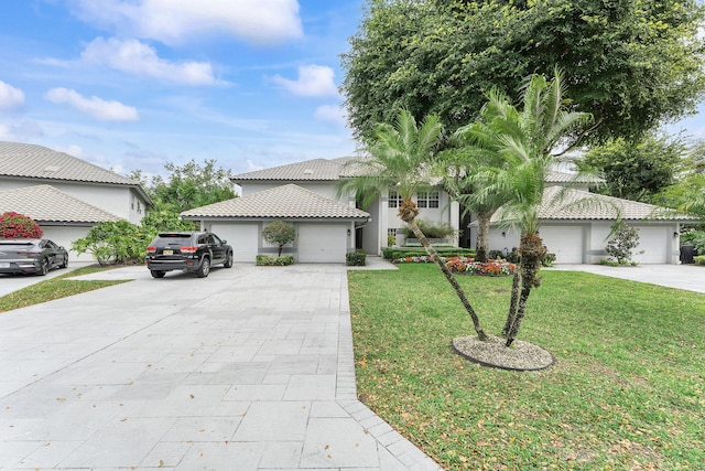 view of front of house featuring a tile roof, driveway, an attached garage, and a front lawn