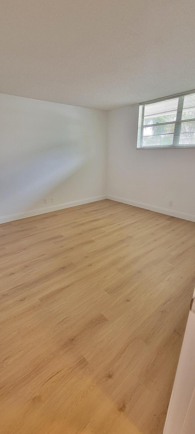 spare room featuring baseboards and light wood-style floors