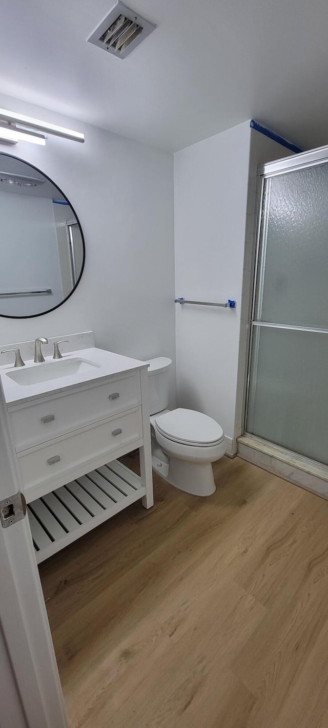 full bath featuring vanity, wood finished floors, visible vents, a stall shower, and toilet