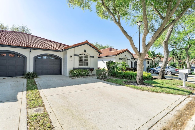 mediterranean / spanish-style home with concrete driveway, a tiled roof, a garage, and stucco siding