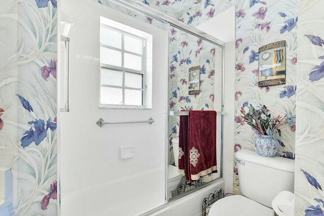 full bathroom featuring wallpapered walls, toilet, and shower / bath combination with glass door