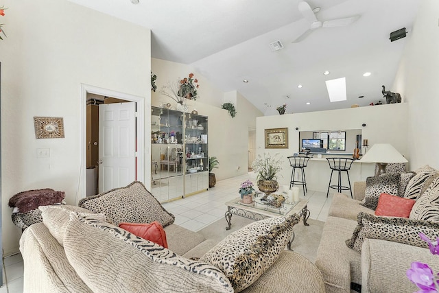 tiled living area with a skylight, a ceiling fan, visible vents, and high vaulted ceiling