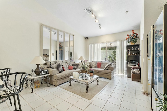 living area with light tile patterned flooring, visible vents, rail lighting, and vaulted ceiling