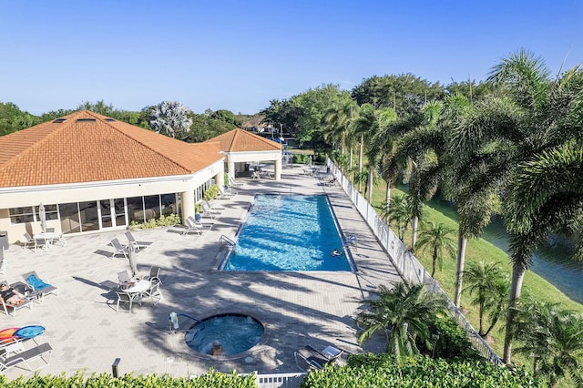 pool with a patio area, fence, and a sunroom