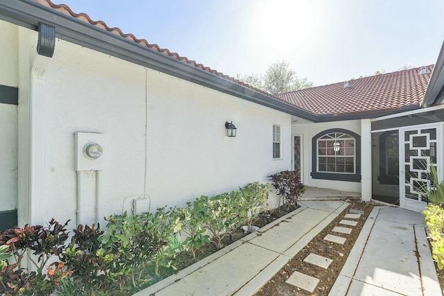 doorway to property featuring stucco siding and a tile roof