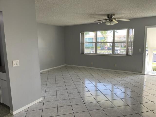 unfurnished room with baseboards, light tile patterned flooring, and a ceiling fan