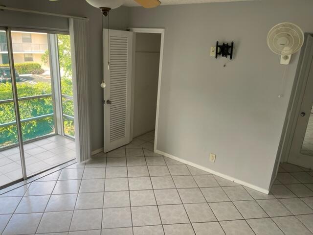 empty room with light tile patterned floors, baseboards, and ceiling fan