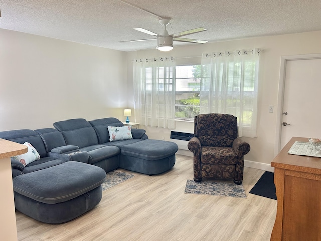 living area featuring ceiling fan, baseboards, light wood finished floors, and a textured ceiling