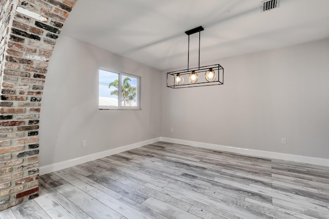 spare room with visible vents, baseboards, and wood finished floors