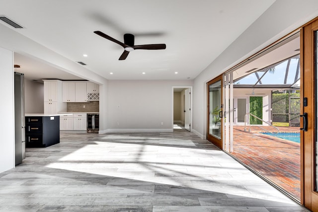 unfurnished living room with visible vents, french doors, light wood-style floors, and a ceiling fan