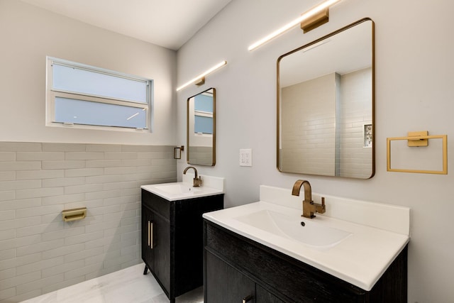 bathroom featuring a sink, tile walls, and two vanities