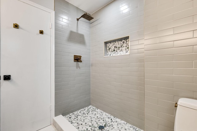 bathroom featuring toilet and a tile shower