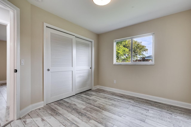 unfurnished bedroom with a closet, baseboards, and light wood-style floors