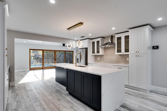 kitchen featuring white cabinetry, wall chimney exhaust hood, stainless steel fridge with ice dispenser, and a sink