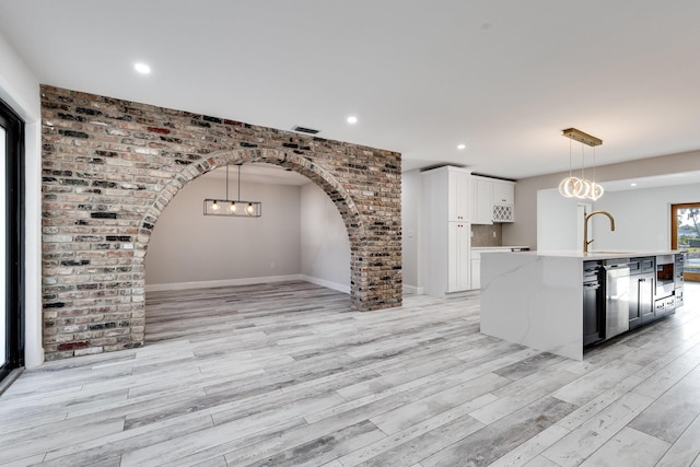 kitchen with visible vents, a sink, white cabinets, light wood-style floors, and stainless steel dishwasher