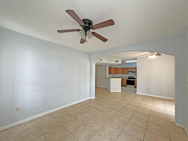 unfurnished living room featuring arched walkways, baseboards, a textured ceiling, and a ceiling fan