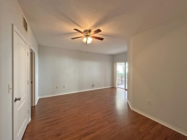 unfurnished room with ceiling fan, visible vents, baseboards, and dark wood-style floors