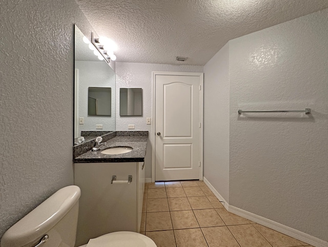 bathroom featuring vanity, tile patterned flooring, a textured ceiling, toilet, and a textured wall