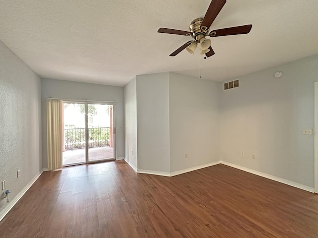 empty room with visible vents, baseboards, dark wood finished floors, a textured wall, and a textured ceiling