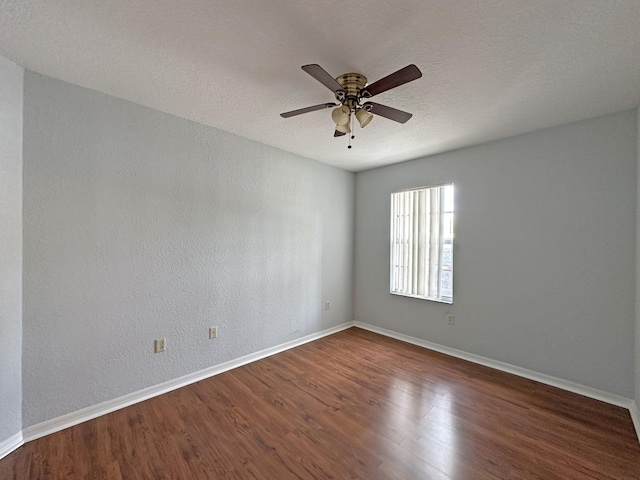 spare room with wood finished floors, baseboards, ceiling fan, a textured ceiling, and a textured wall