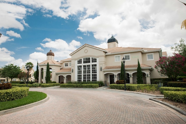 view of front of home featuring stucco siding, decorative driveway, a chimney, and a tile roof