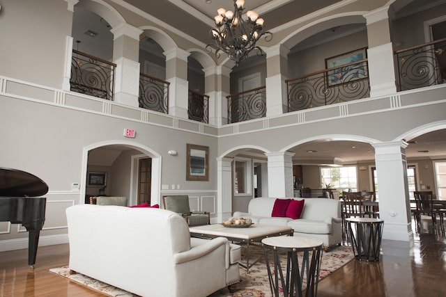 living room with ornamental molding, wood finished floors, a high ceiling, a decorative wall, and decorative columns