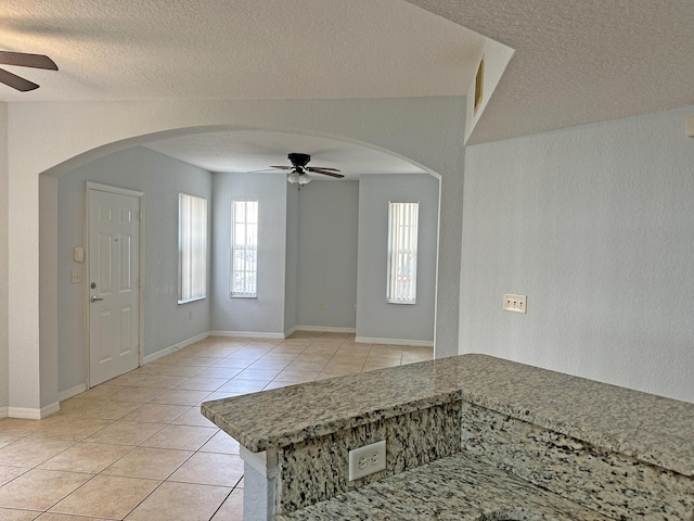 foyer entrance with light tile patterned floors, a healthy amount of sunlight, arched walkways, and ceiling fan