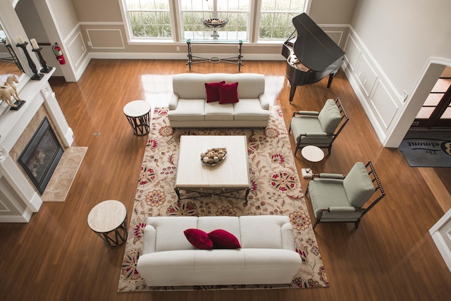 living room featuring a fireplace with flush hearth, a decorative wall, and wood finished floors