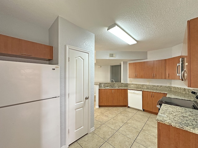 kitchen featuring brown cabinetry, visible vents, a sink, stainless steel appliances, and a textured ceiling