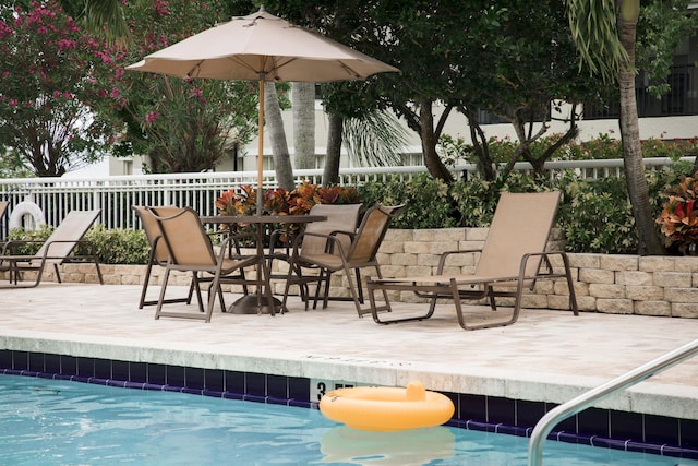 pool with outdoor dining area, a patio area, and fence