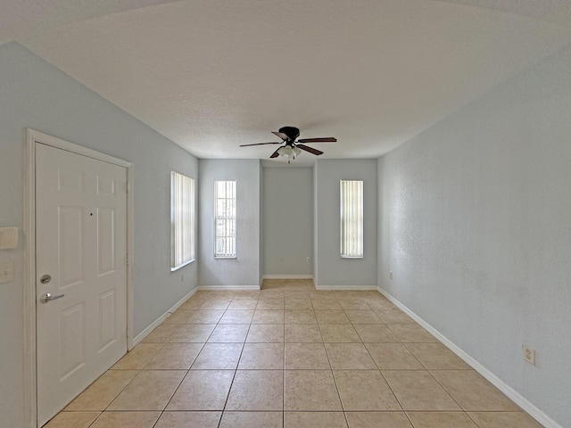 spare room with light tile patterned floors, baseboards, a textured ceiling, and ceiling fan