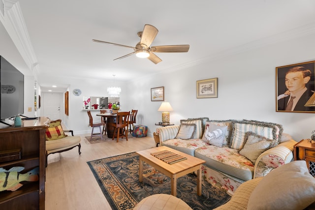 living area featuring baseboards, wood finished floors, crown molding, and ceiling fan with notable chandelier