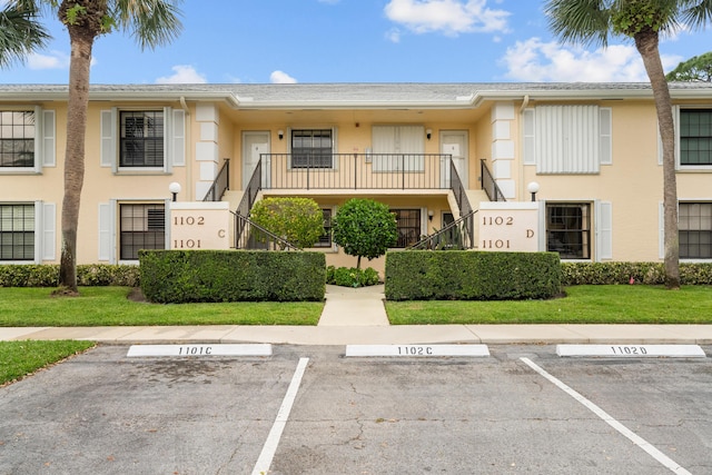 view of property with stairs and uncovered parking