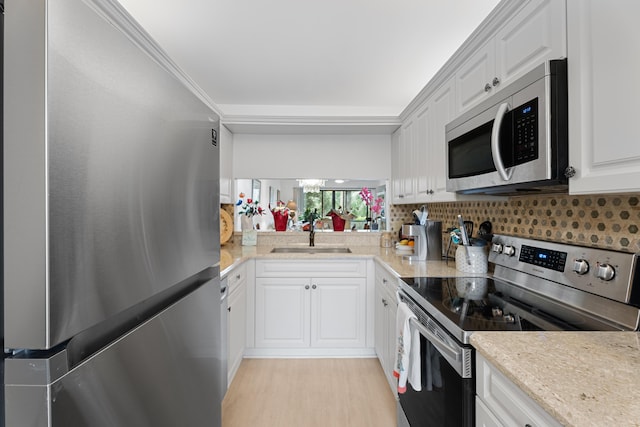 kitchen featuring backsplash, white cabinets, stainless steel appliances, and a sink