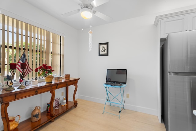 home office with a ceiling fan, light wood-type flooring, and baseboards