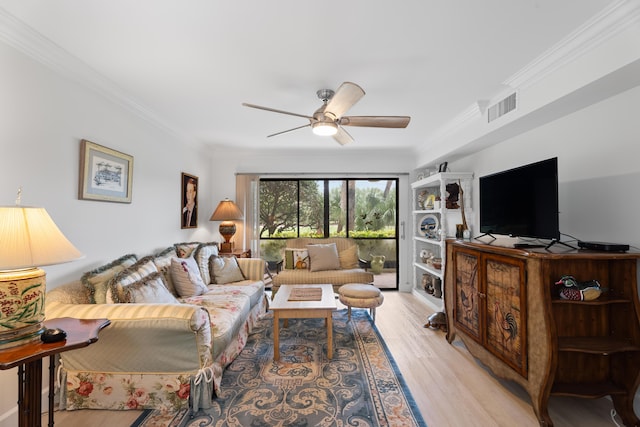 living room with light wood-type flooring, visible vents, ornamental molding, and ceiling fan