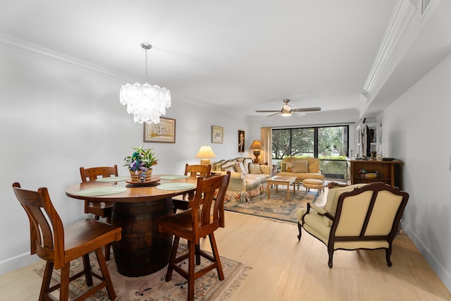 dining room featuring baseboards, ceiling fan with notable chandelier, ornamental molding, and light wood finished floors