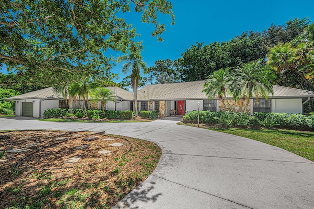 view of front of property with concrete driveway, a tiled roof, a garage, and stucco siding