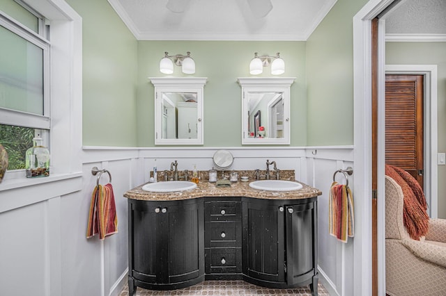 bathroom featuring a sink, a wainscoted wall, and ornamental molding