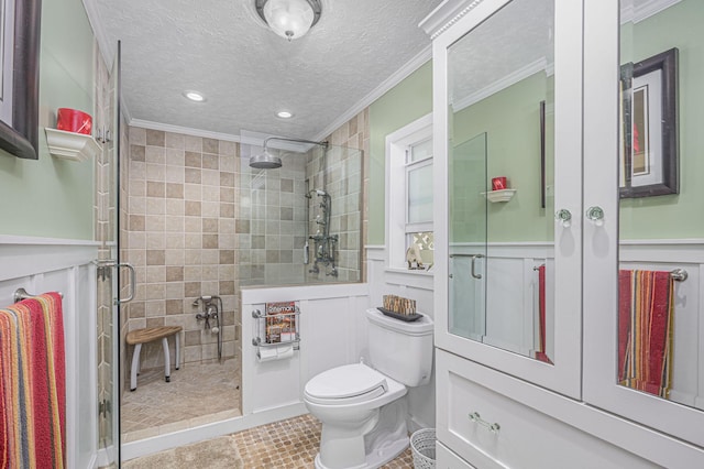 bathroom with a textured ceiling, toilet, a stall shower, and ornamental molding