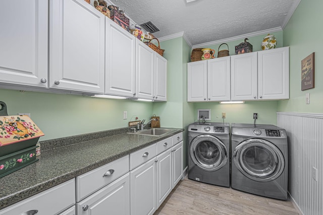 laundry room with light wood-type flooring, washer and dryer, a sink, cabinet space, and crown molding