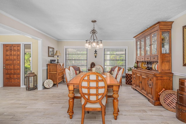 dining room with light wood finished floors, a textured ceiling, an inviting chandelier, and ornamental molding