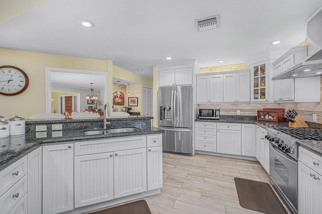 kitchen featuring visible vents, a sink, decorative backsplash, appliances with stainless steel finishes, and wall chimney range hood