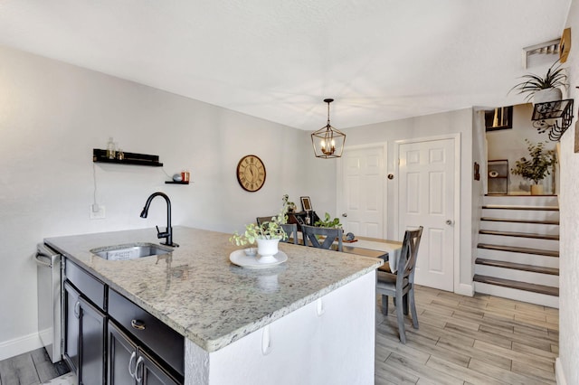 kitchen with light stone counters, baseboards, wood finish floors, and a sink