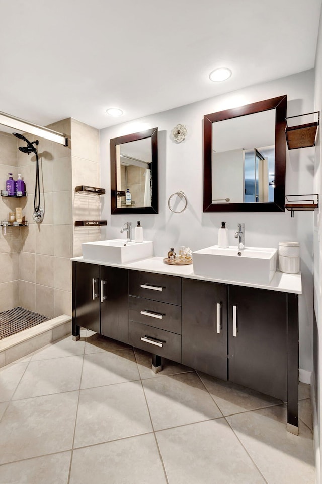 full bath featuring tile patterned flooring, double vanity, a tile shower, and a sink