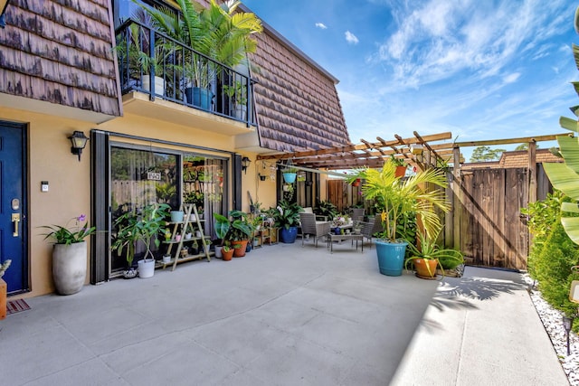 view of patio with a balcony, fence, and a pergola