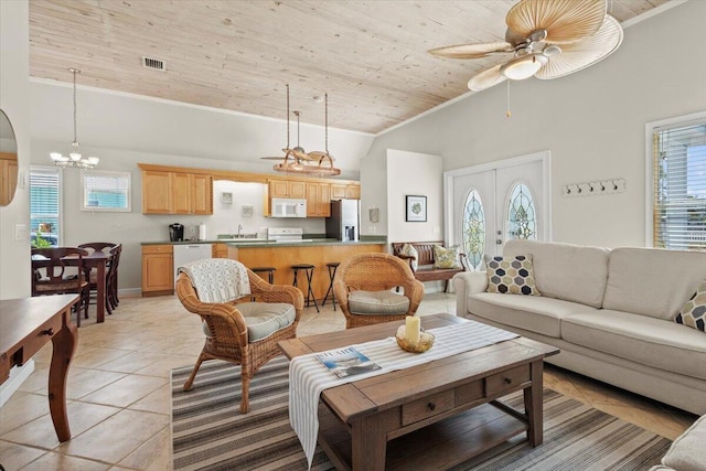 living area with visible vents, crown molding, light tile patterned floors, a wealth of natural light, and high vaulted ceiling