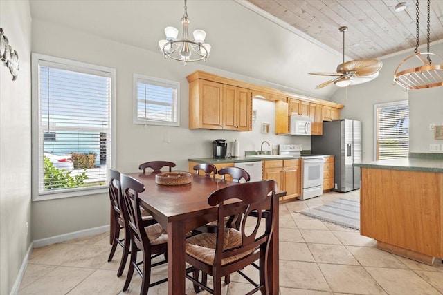 dining room with light tile patterned flooring, a healthy amount of sunlight, baseboards, and lofted ceiling