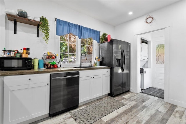 kitchen featuring a sink, black appliances, stacked washer and dryer, white cabinetry, and open shelves