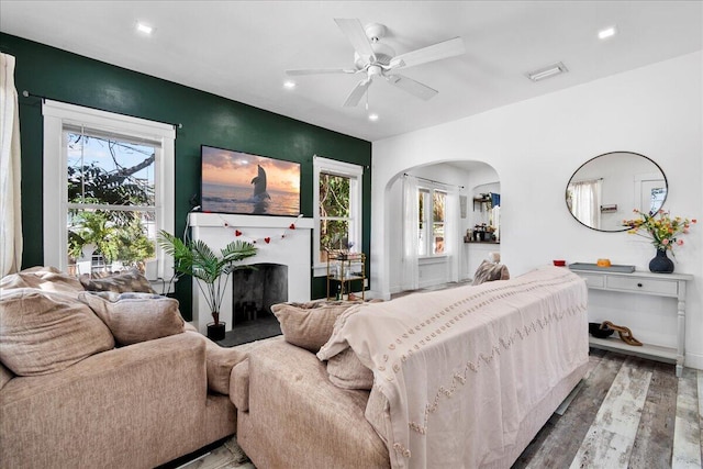 bedroom featuring wood finished floors, visible vents, a fireplace, recessed lighting, and arched walkways